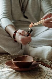 Close-up of hands holding and lighting a Palo Santo stick for spiritual cleansing.