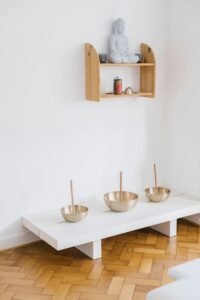 Serene home interior featuring Buddha statue and Tibetan singing bowls on a wooden shelf.